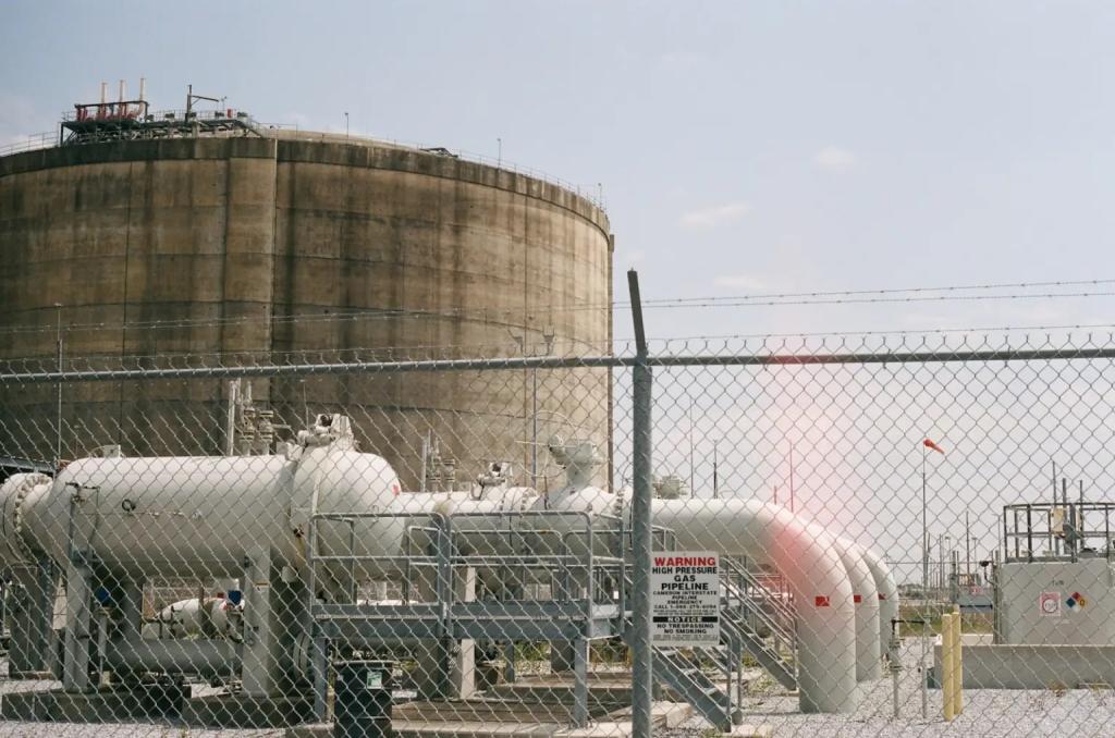 a large cylindrical piece of equipment with pipes behind a chain link fence