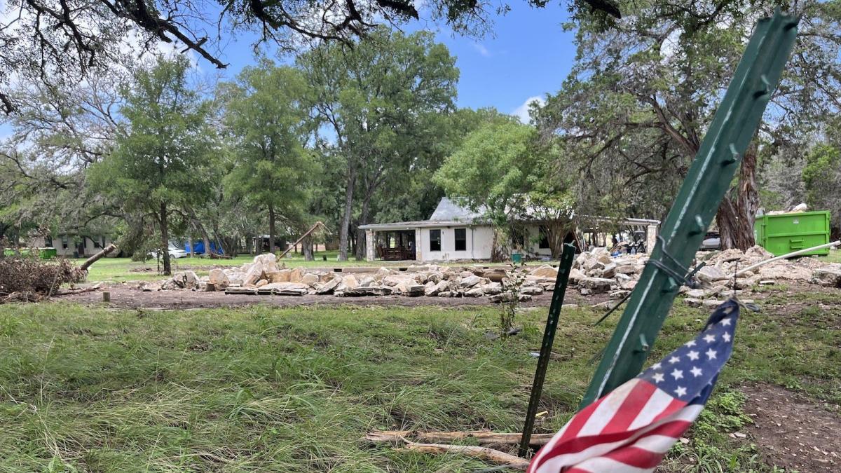 A flood-damaged house with a US flag flying outside of it