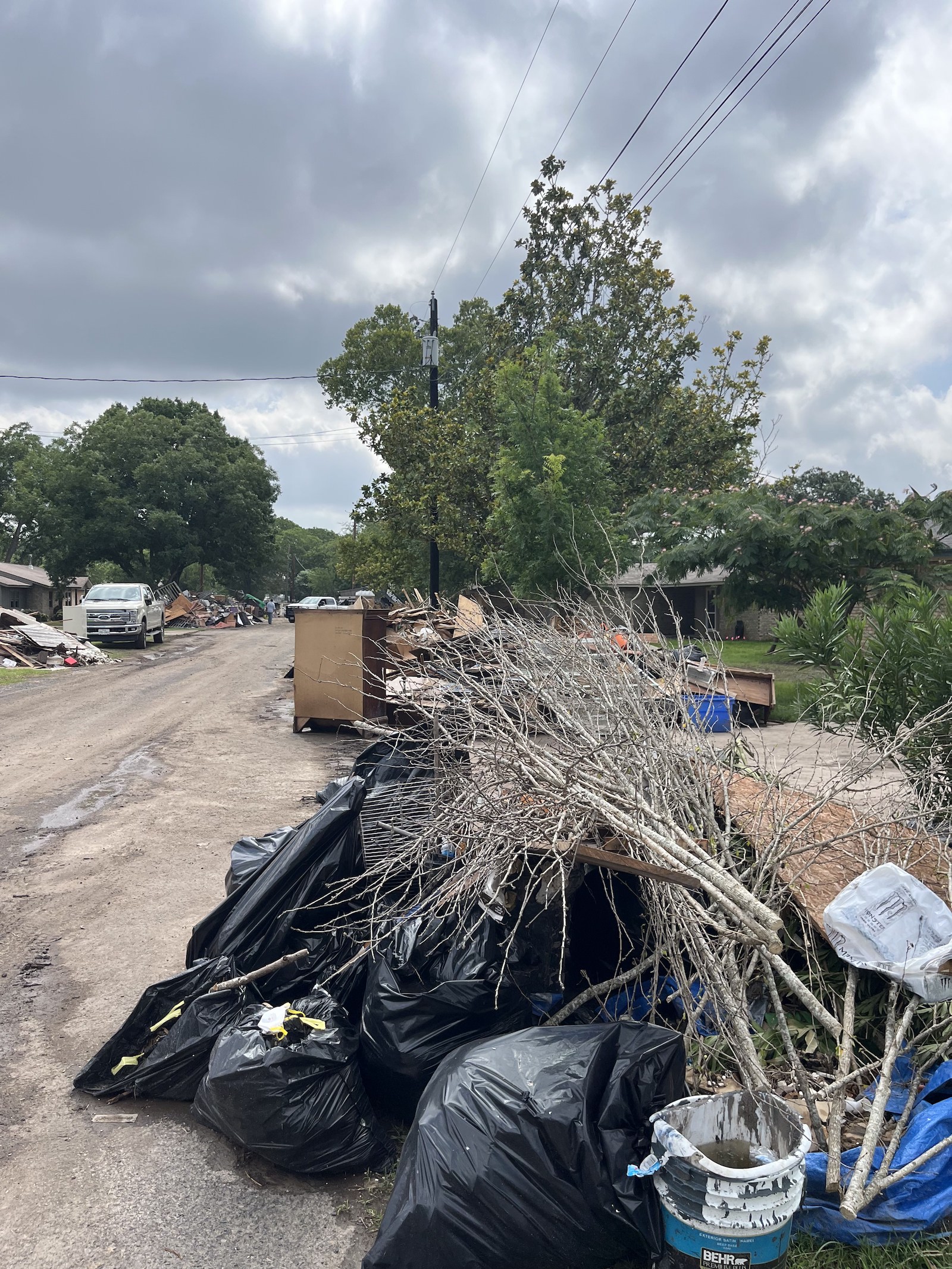 A pile of garbage bags by the side of a flood-damaged street