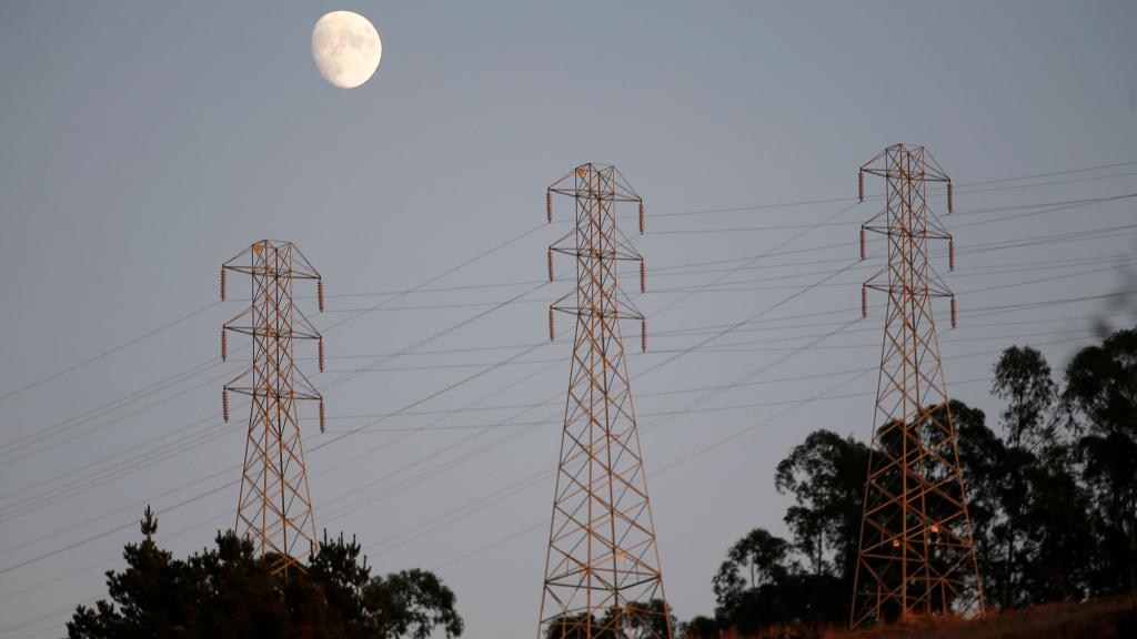 Utulity lines are seen in the hills above Oakland as the moon rises above them.