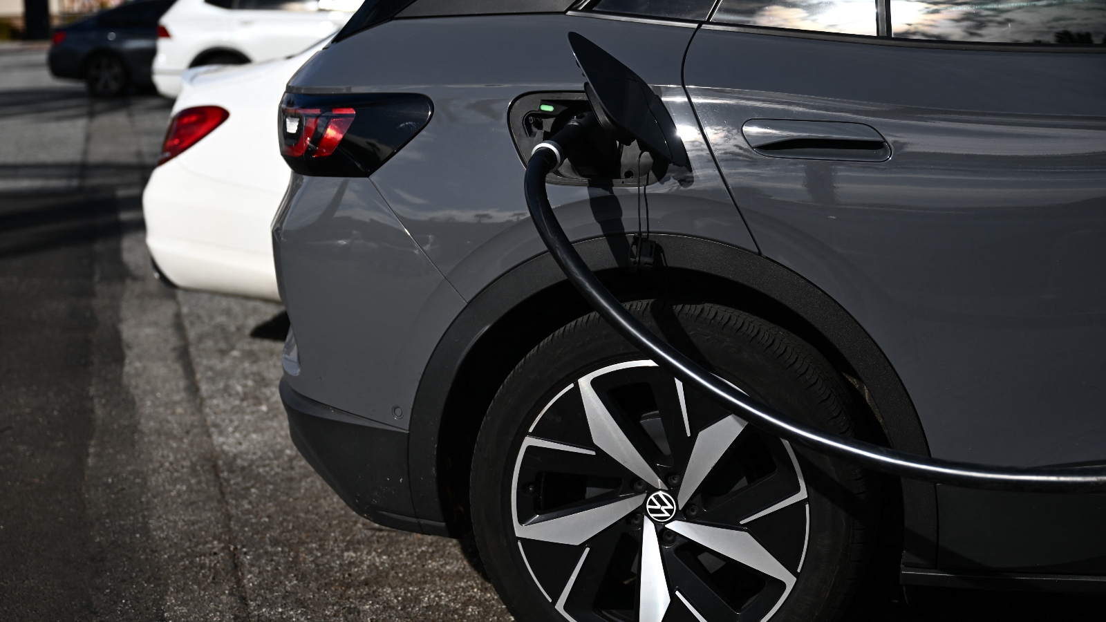 A black car is hooked up to a black charging cable