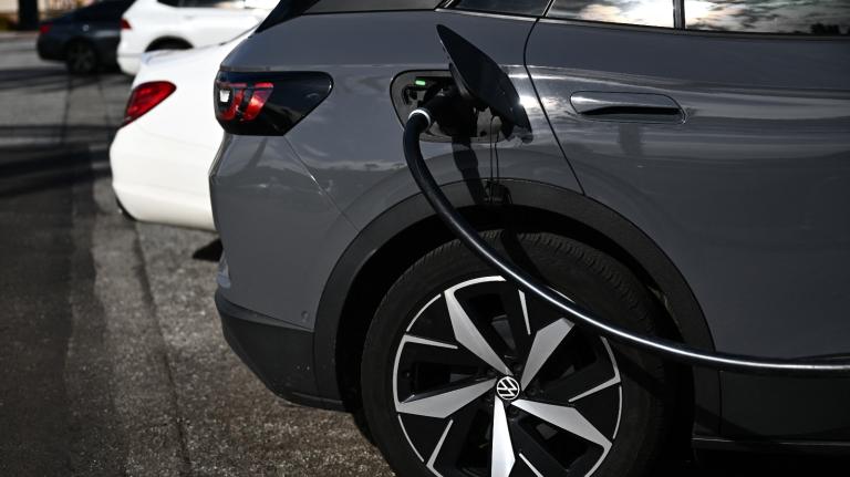 A black car is hooked up to a black charging cable