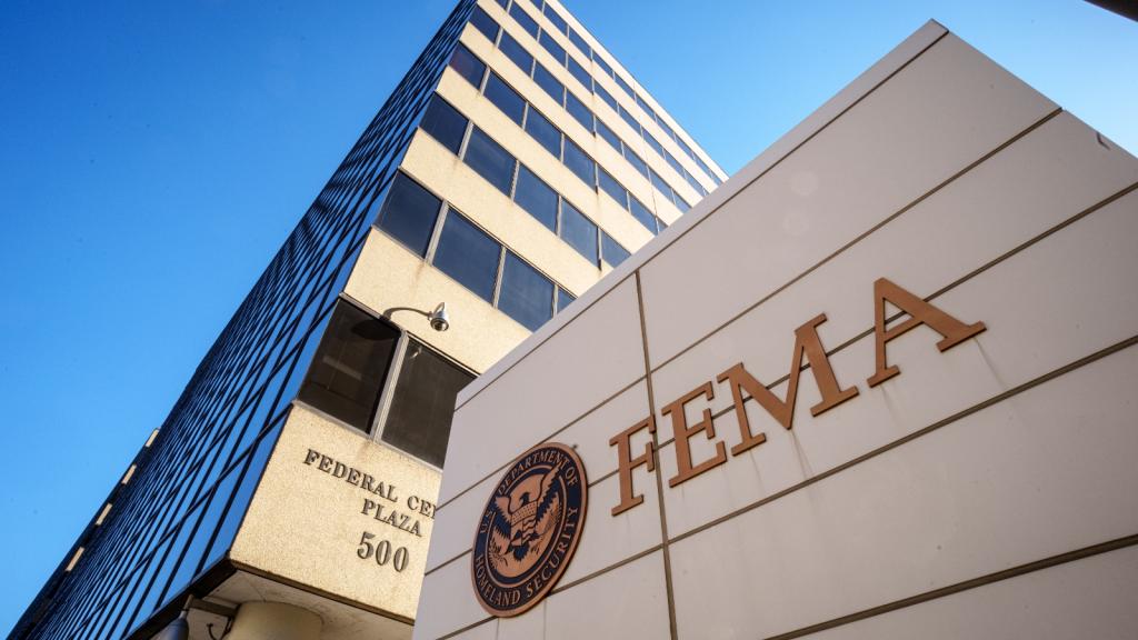 Two white buildings tower in front of a blue sky and one reads FEMA