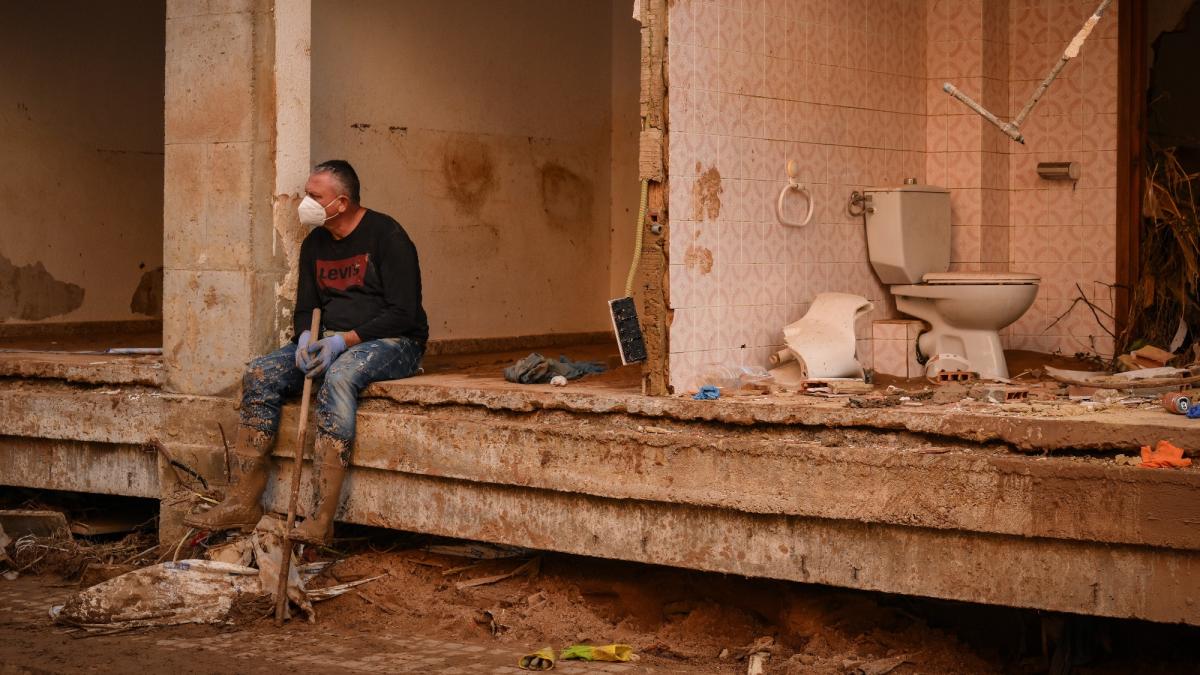 A resident sits on a wall of a collapsed house damaged by widespread flooding near Valencia, Spain in November 2024.