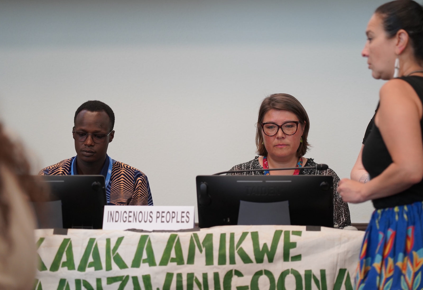Two people sit at a panel with a placard indicating, "indigenous peoples."