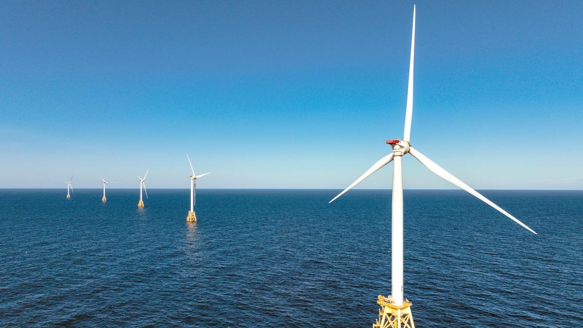 Several wind turbines stand in the middle of the ocean