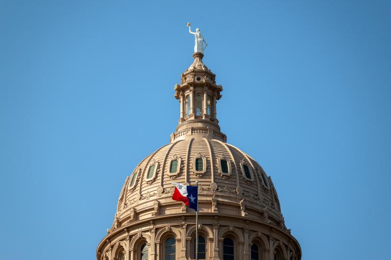 Texas flag flying beneath legislative building