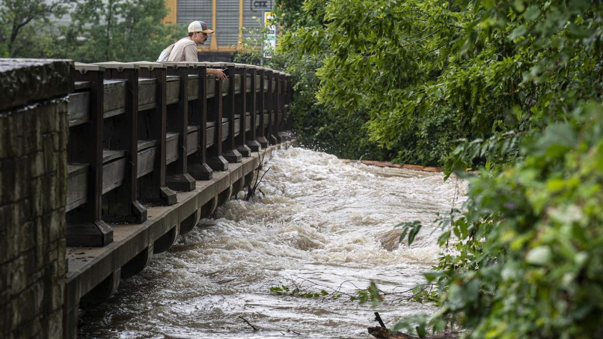 A man watches the Menomonee River flow under a bridge on August 10, 2025 in Wauwatosa, Wisconsin. Heavy downpours brought as much as 13 inches of rain to parts of southeast Wisconsin overnight causing floods across the region.