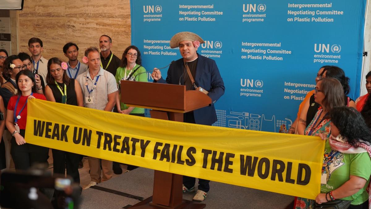 A man in a wide-brimmed hat stands at a podium in front of a banner reading, "Weak UN treaty fails the world." A blue background behind him.