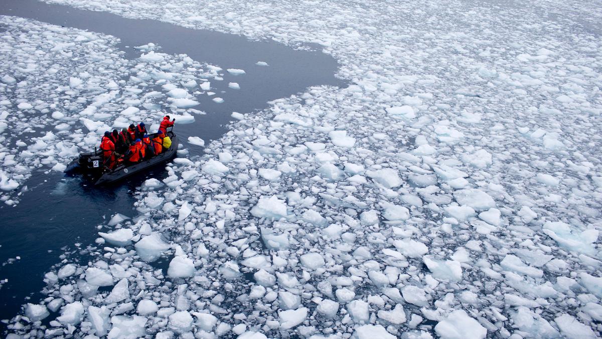 A boat of researchers on the sea in Antarctica surrounded by ice
