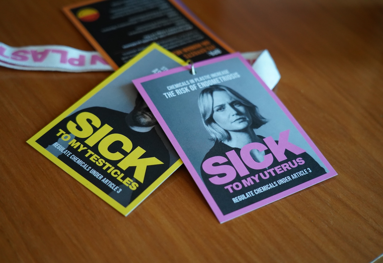 Two cards on a table. The top one features a black-and-white portrait of a woman with the message, "sick to my uterus," and the one below says "sick to my testicles."
