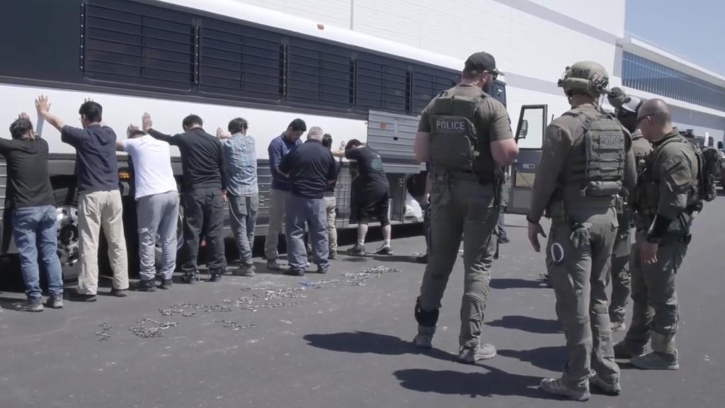This image from video provided by U.S. Immigration and Customs Enforcement via DVIDS shows manufacturing plant employees waiting to have their legs shackled at the Hyundai Motor Group’s electric vehicle plant, Thursday, Sept. 4, 2025, in Ellabell, Ga.
