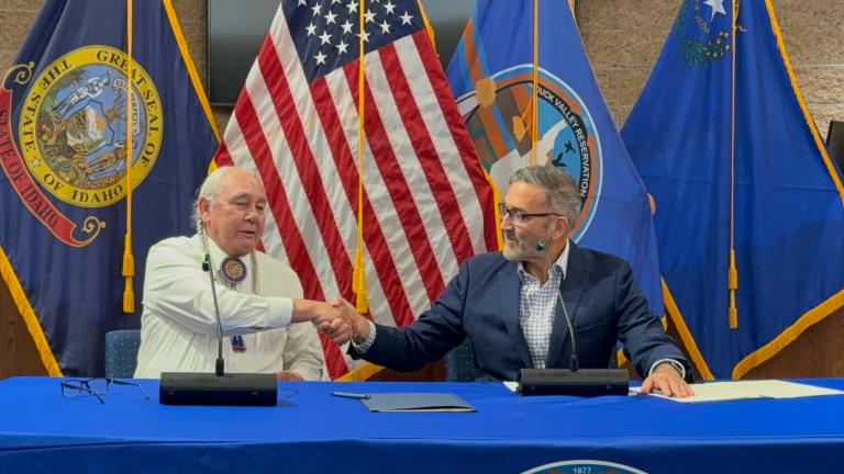 Two men shaking hands in front of flags