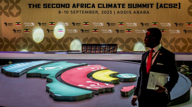 A delegate stands in front of a backdrop for the Second Africa Climate Summit during the opening of the summit in Addis Ababa.