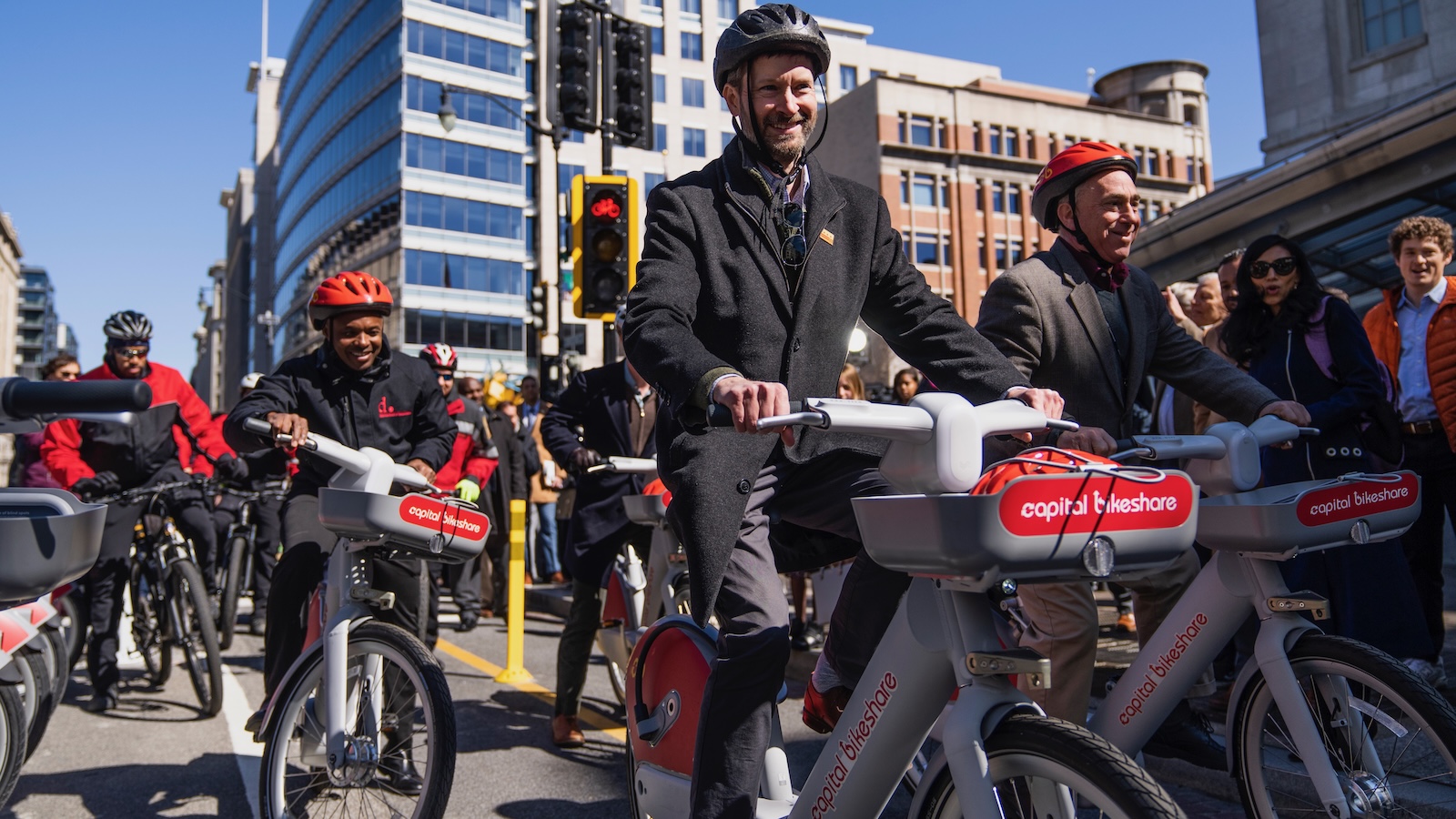 A crowd of people ride e-bikes in downtown Washington DC