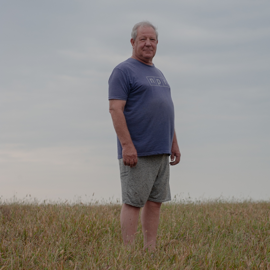 In a grid of four photos, the first one shows a man wearing a T-shirt and shorts standing in a field, and the other three show blackened oil and gas wells. One sticks up near a tree and sits in a circle of black amid a field of grass, one is an elbow of pipe with wet and blackened ground beneath it, and one is a rusty stub of pipe sticking straight up out of the ground.