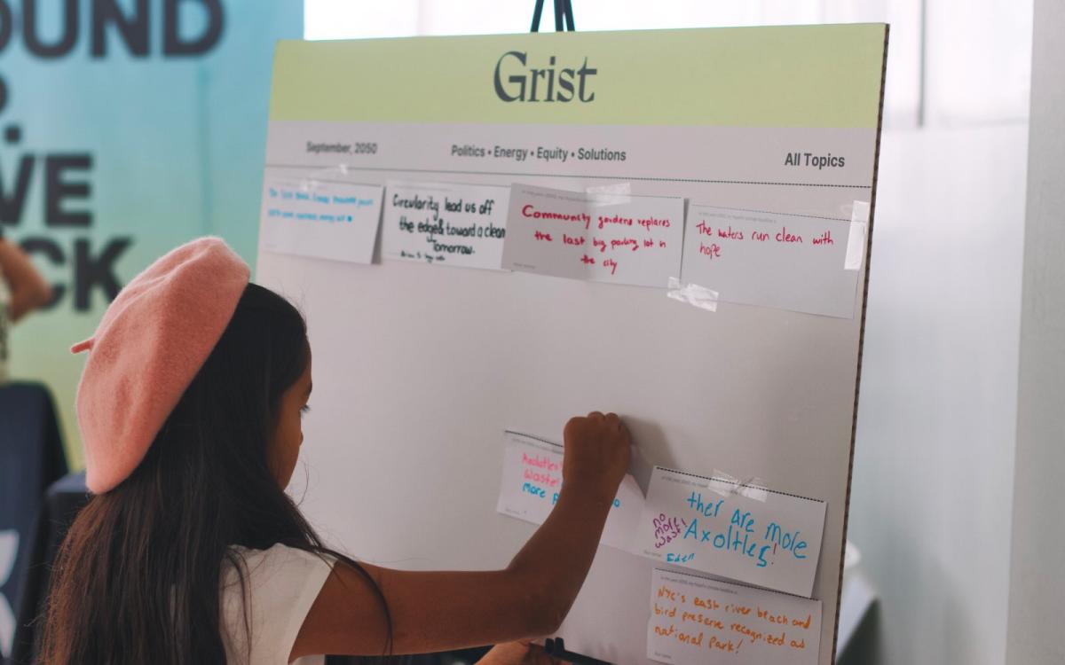A young girl places a note card on a poster board
