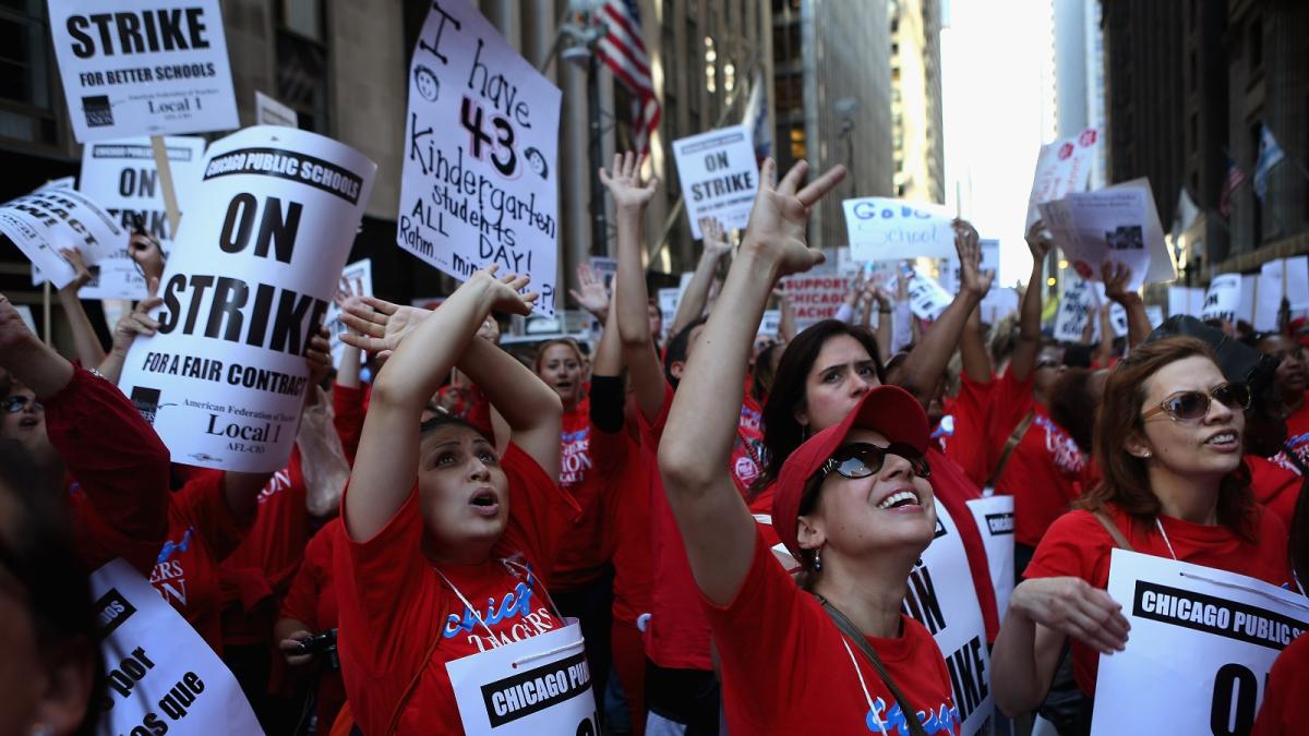 A group of people in red shirts cheer with signs