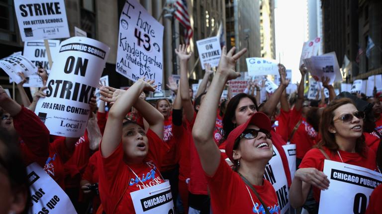A group of people in red shirts cheer with signs