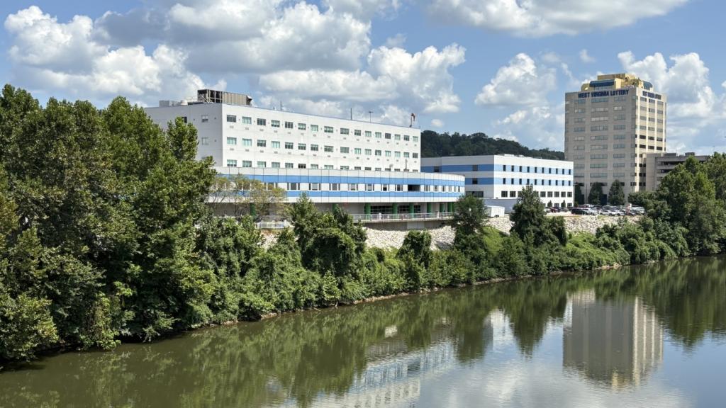 A large white and blue building sits on the banks of a river