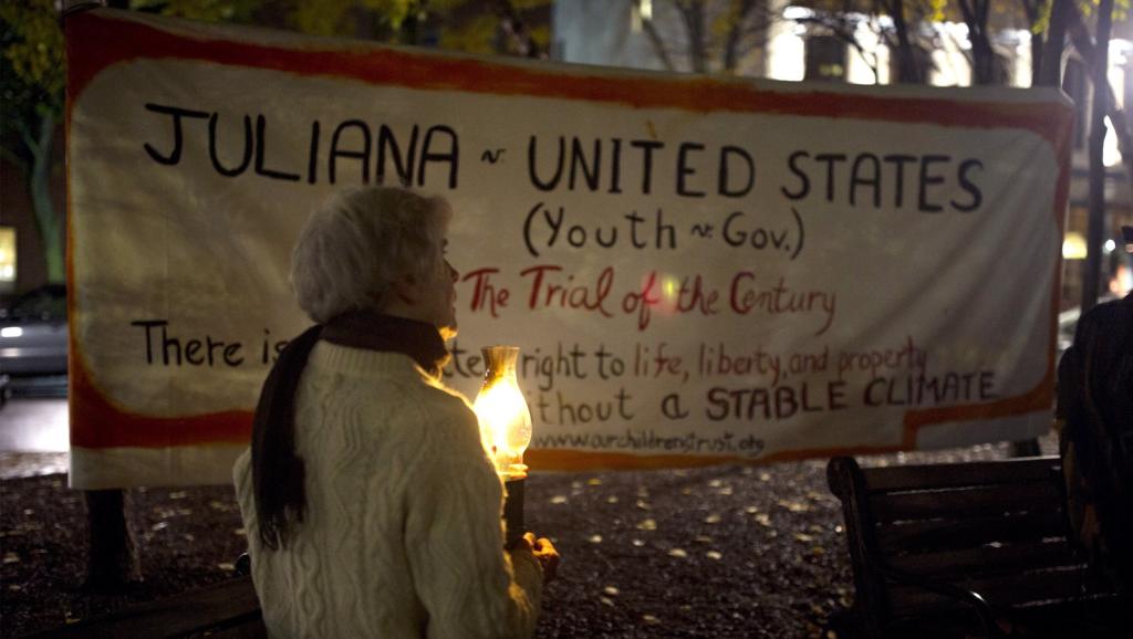 Molly Wilcox, of Damariscotta,holds a candle in front of a sign supporting Juliana v. US during a candlelight rally organized by 350 Maine in support of the plaintiffs in downtown Portland on Monday, October 29, 2018.