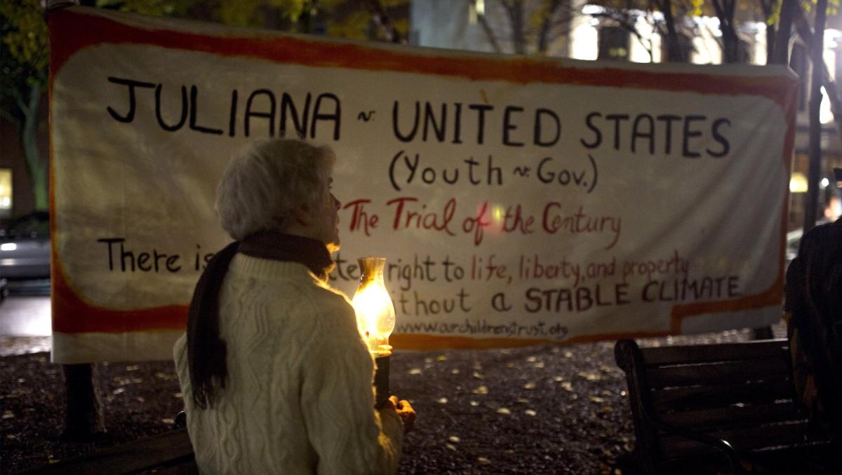 Molly Wilcox, of Damariscotta,holds a candle in front of a sign supporting Juliana v. US during a candlelight rally organized by 350 Maine in support of the plaintiffs in downtown Portland on Monday, October 29, 2018.