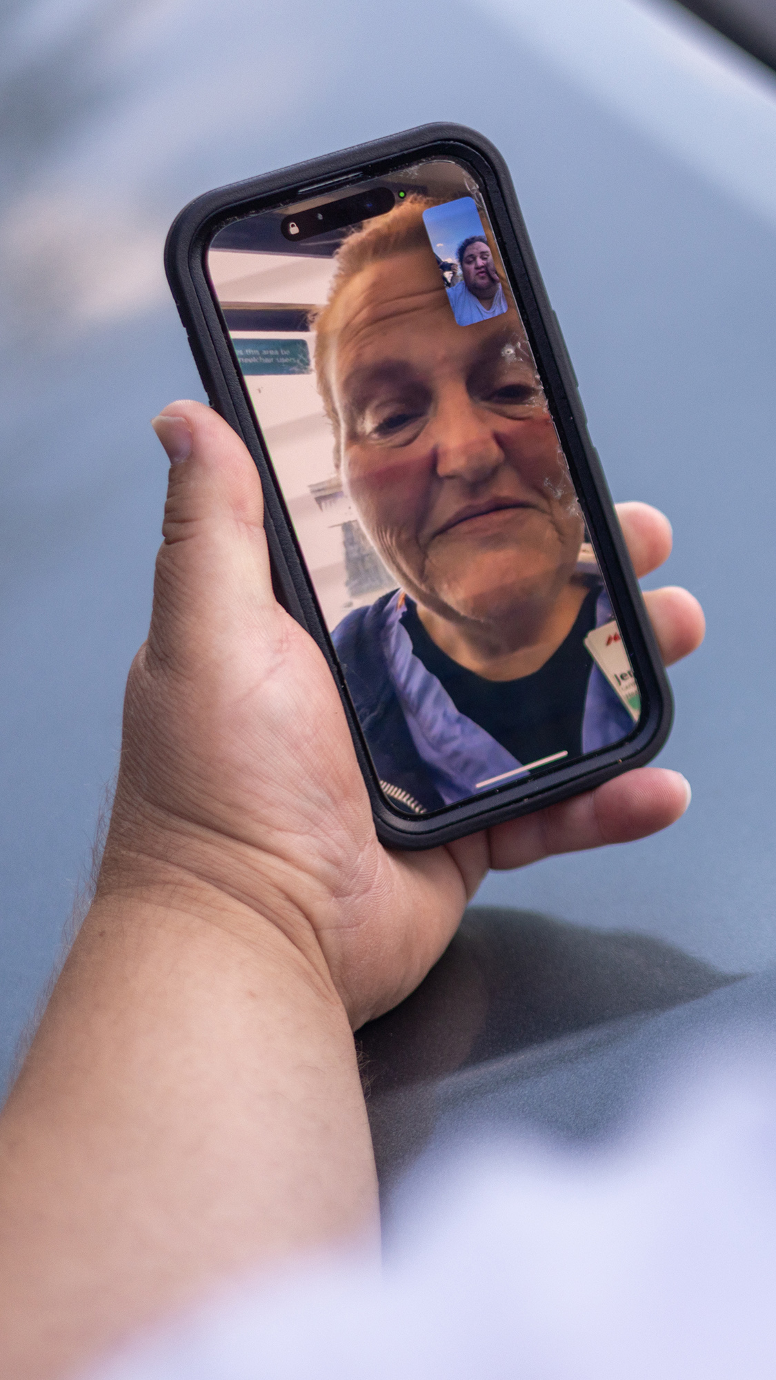 a man's arm holds a smart phone showing a woman in a nurse's uniform during a facetime call