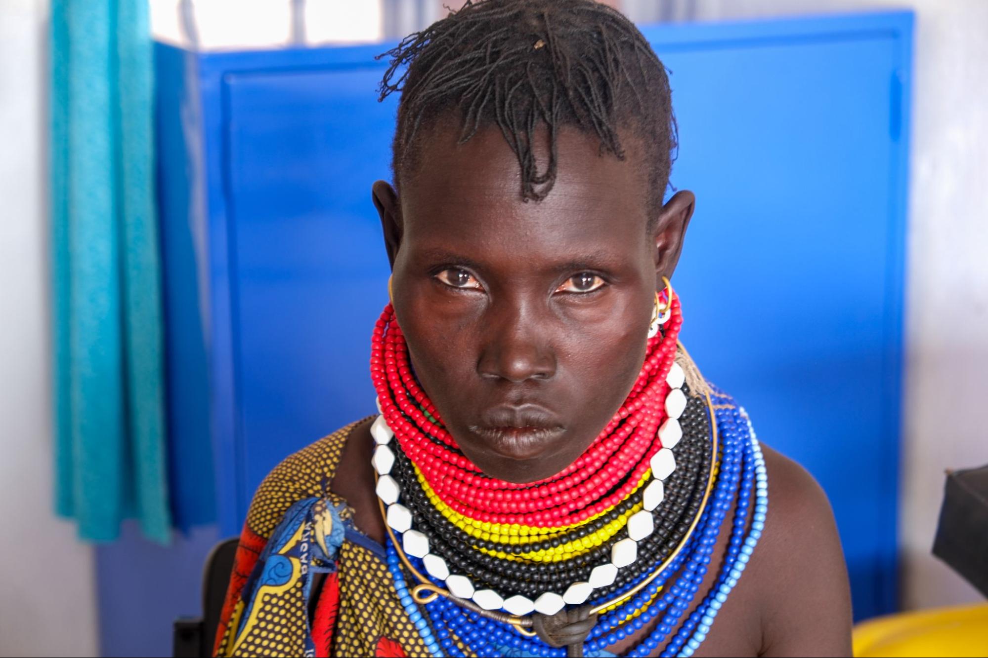 A woman wearing colorful beaded necklaces while looking directly into the camera