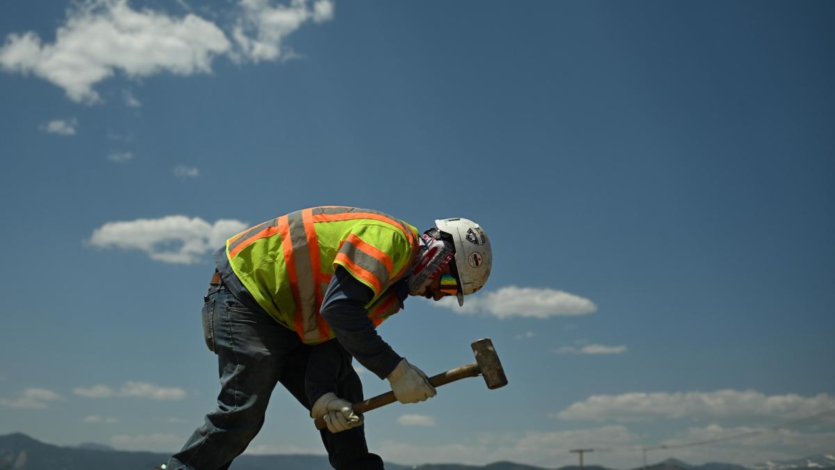 construction worker swings a sledgehammer during high 90-degree temperatures