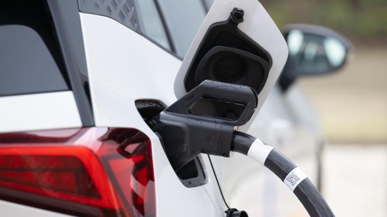 A white electric vehicle has a charger attached to it