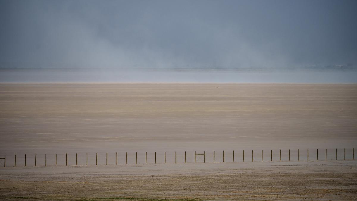 A fence cuts across the dry landscape of the Great Salt Lake in Utah.