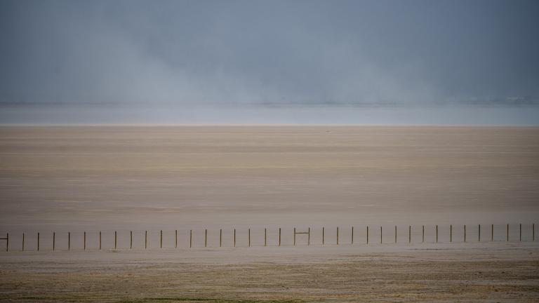 A fence cuts across the dry landscape of the Great Salt Lake in Utah.
