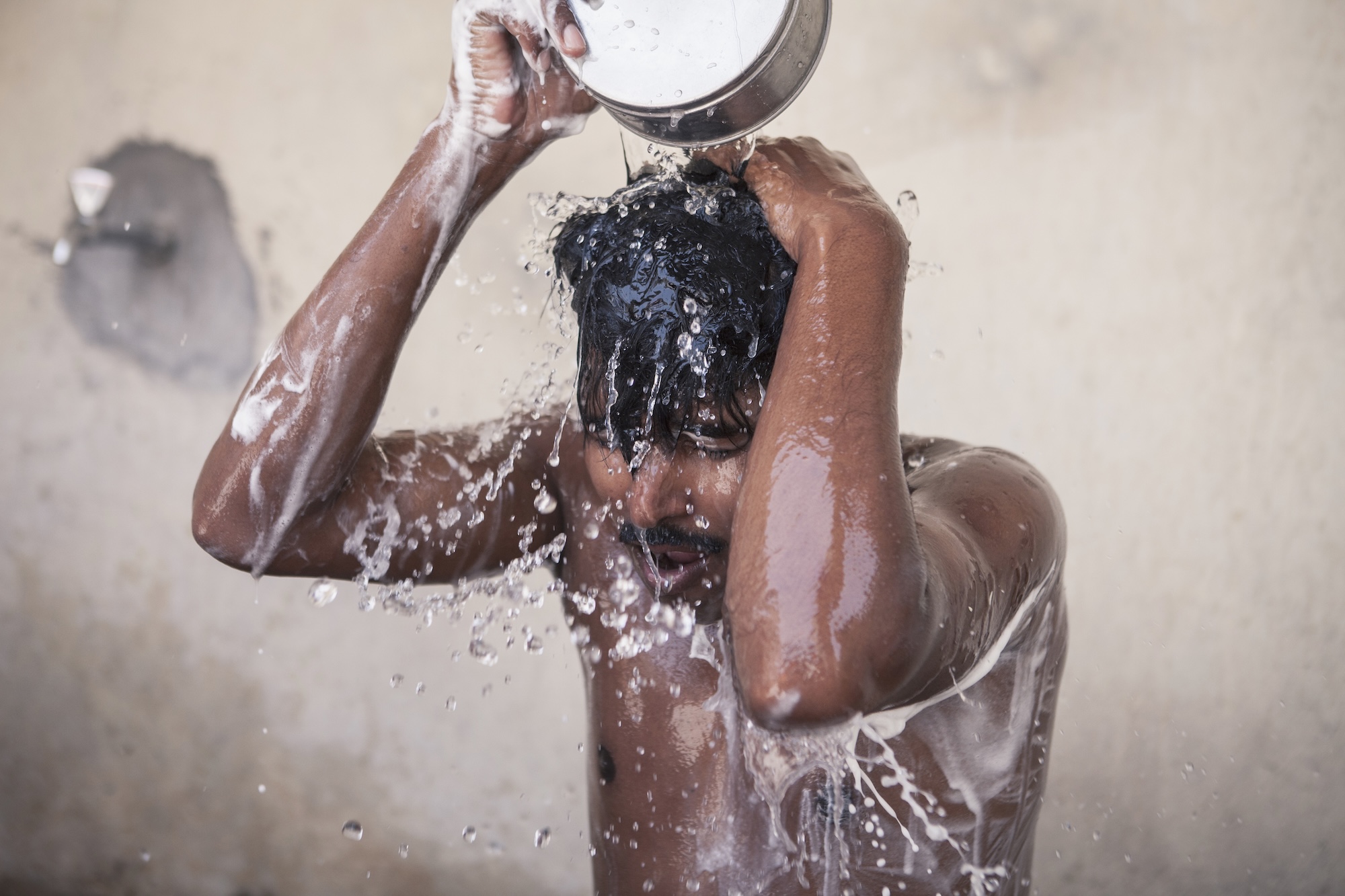A man dumps water on his head from a basin