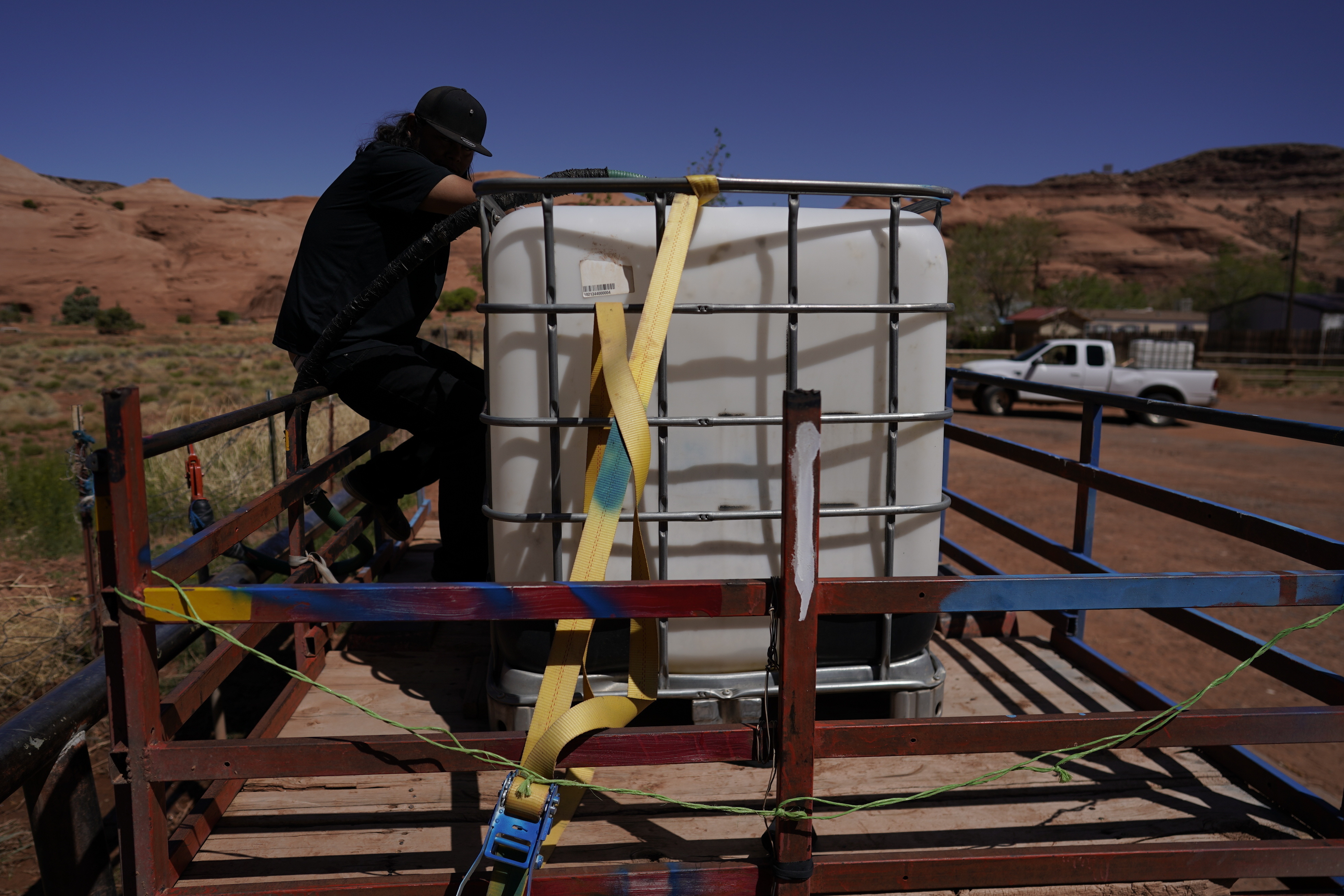 Someone is standing on top of a truck trailer with a water tank.