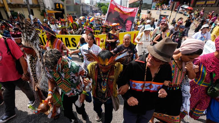 Activists participate in a climate protest during the COP30 U.N. Climate Summit, Saturday, Nov. 15, 2025, in Belem, Brazil. The photo shows people linking hands and walking on a road.