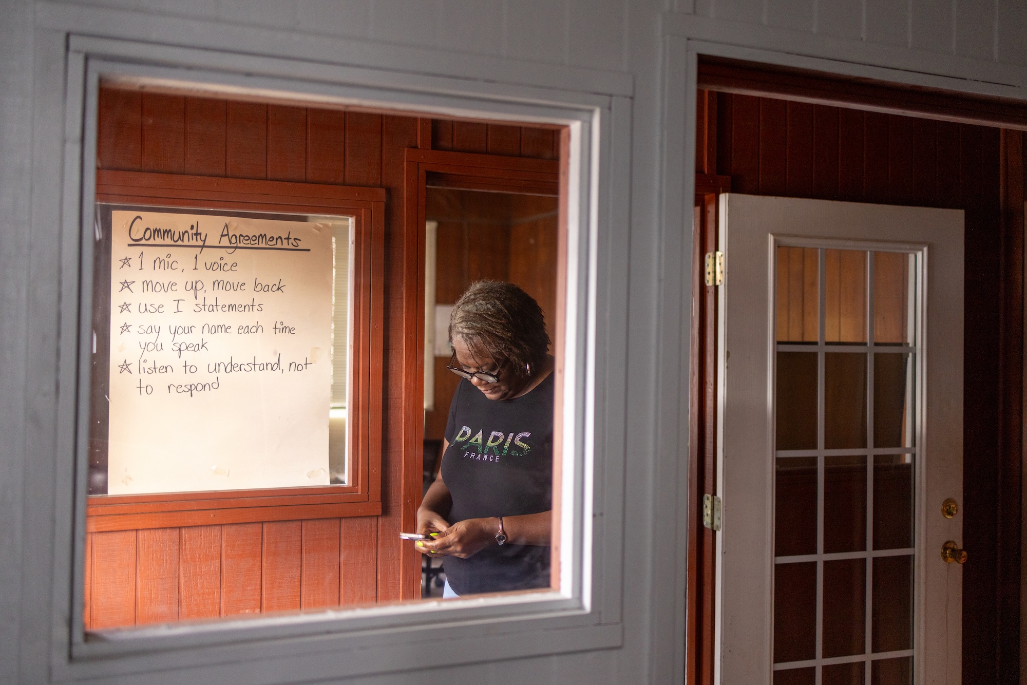 A woman checker her phone in a room with a white board