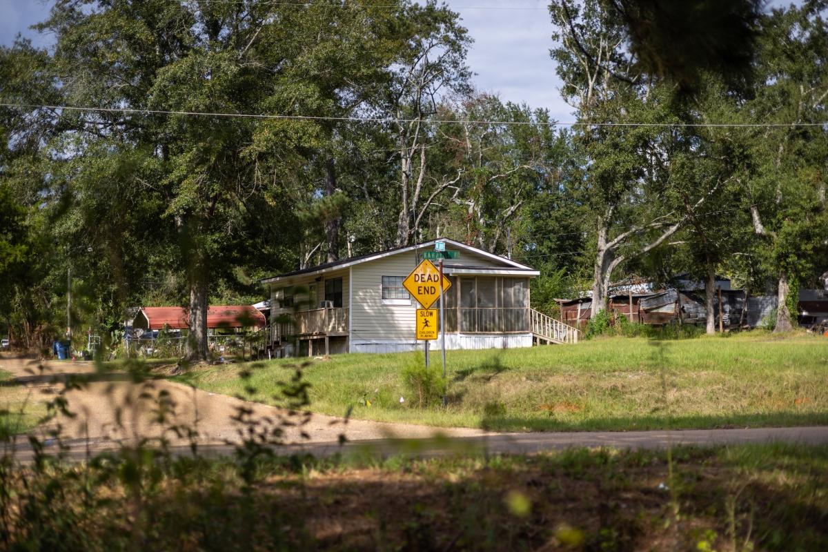 a dead end sign near a house in a residential area with greenery
