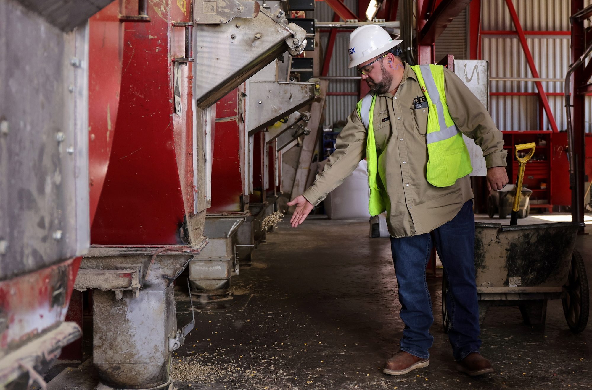 a man in a neon vest and hard hat handle pelletes in a factory