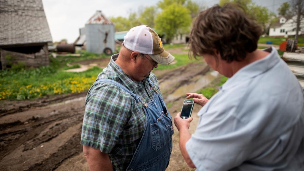 Farmer Sid Ready looks at his wife's smart phone to check the weather radar of the approaching storm on his farm near Scribner, Nebraska in 2019.