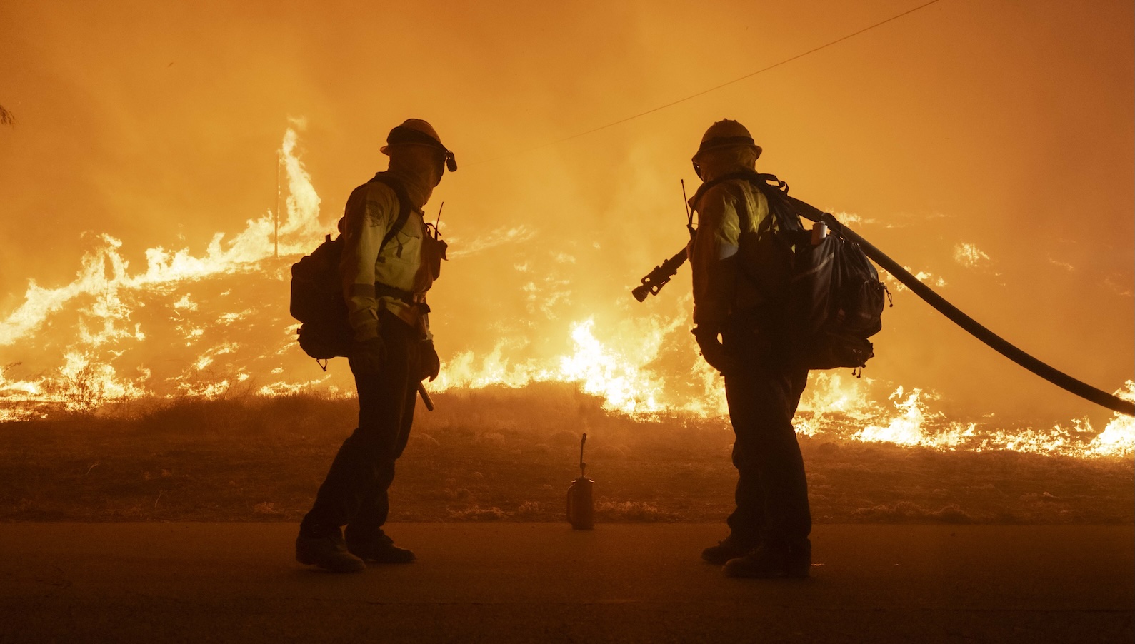 How the planet fared in 2025 — the good, the bad, and the ugly two firefighters look at a wildfire