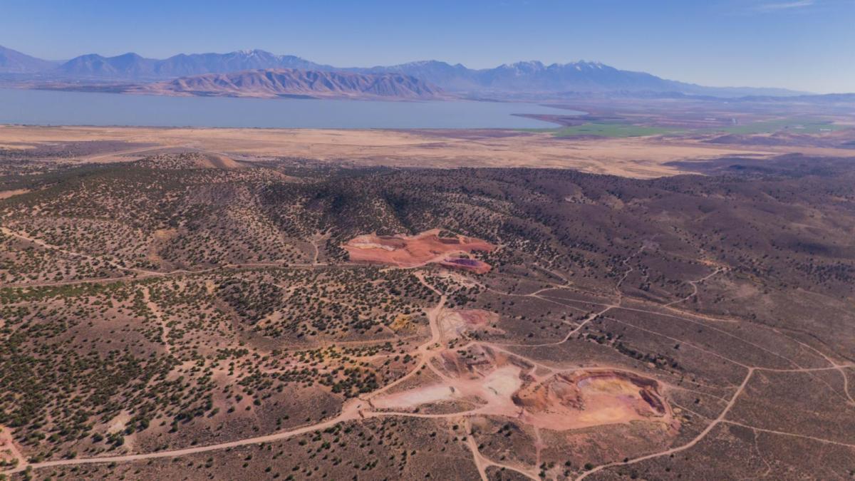 Disturbed earth from mining is visible with a lake and mountains in the background.