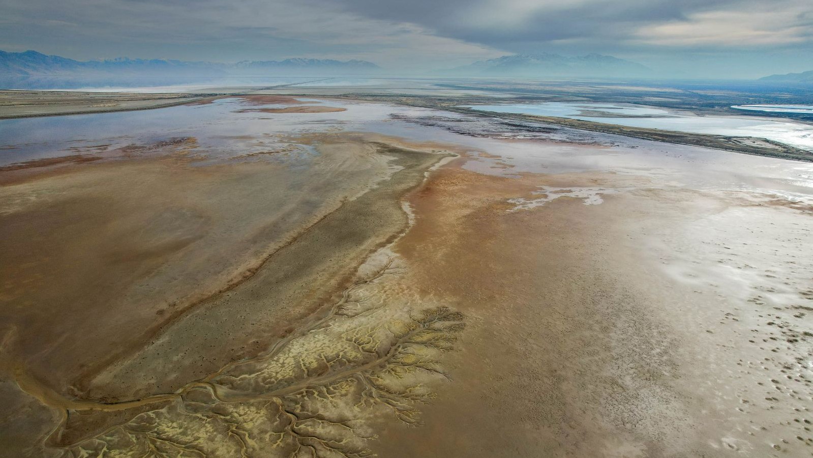 A colorful playa and the Great Salt Lake with mountains in the background