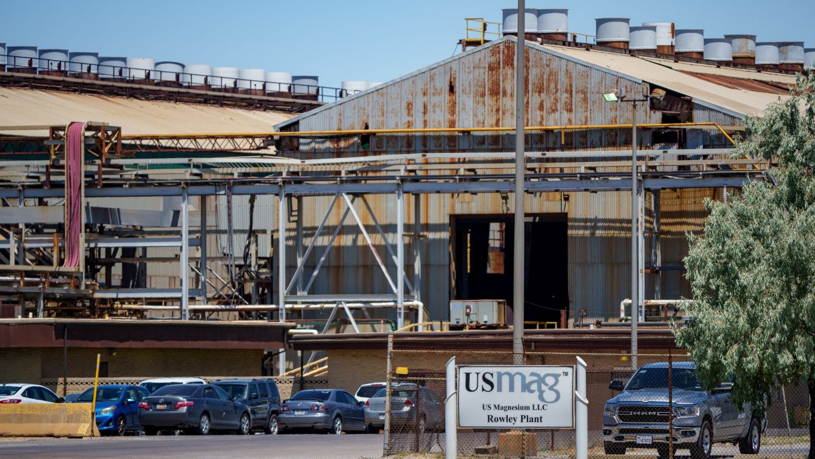An industrial building with parked cars and a sign.