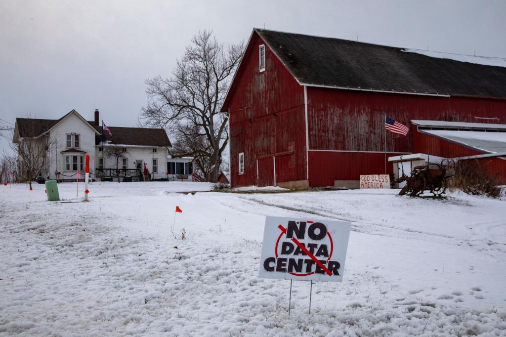 Red barn in snow with a 'no data center' protest sign in the yard