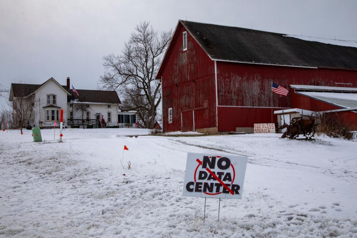 Red barn in snow with a 'no data center' protest sign in the yard