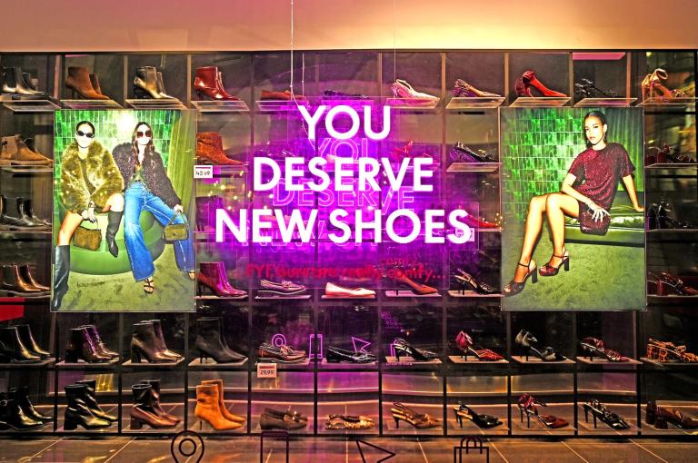 A display of shoes with a neon sign that reads 'You deserve new shoes' in the shop window of a New Look fashion retail store on November 10, 2025 in London, United Kingdom.