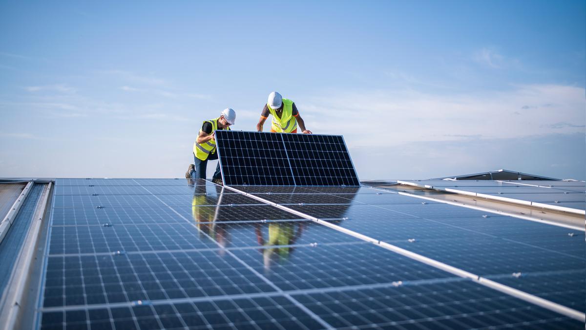 Two engineers installing solar panels on roof.