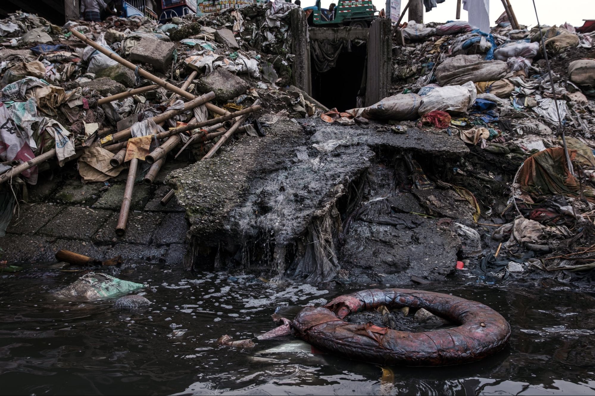 a large pile of trash leads to a waterway. Runoff adds to the water