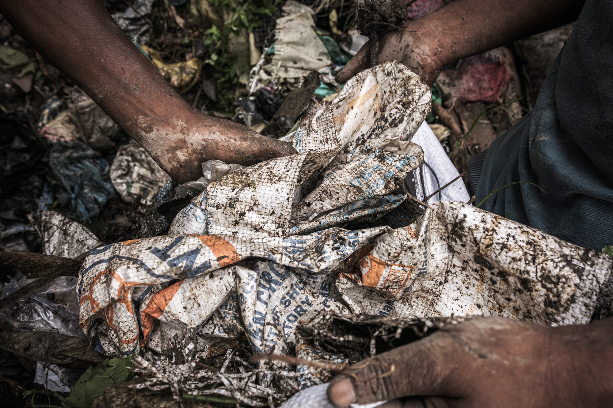 hands pick up a dirty bunched up bag