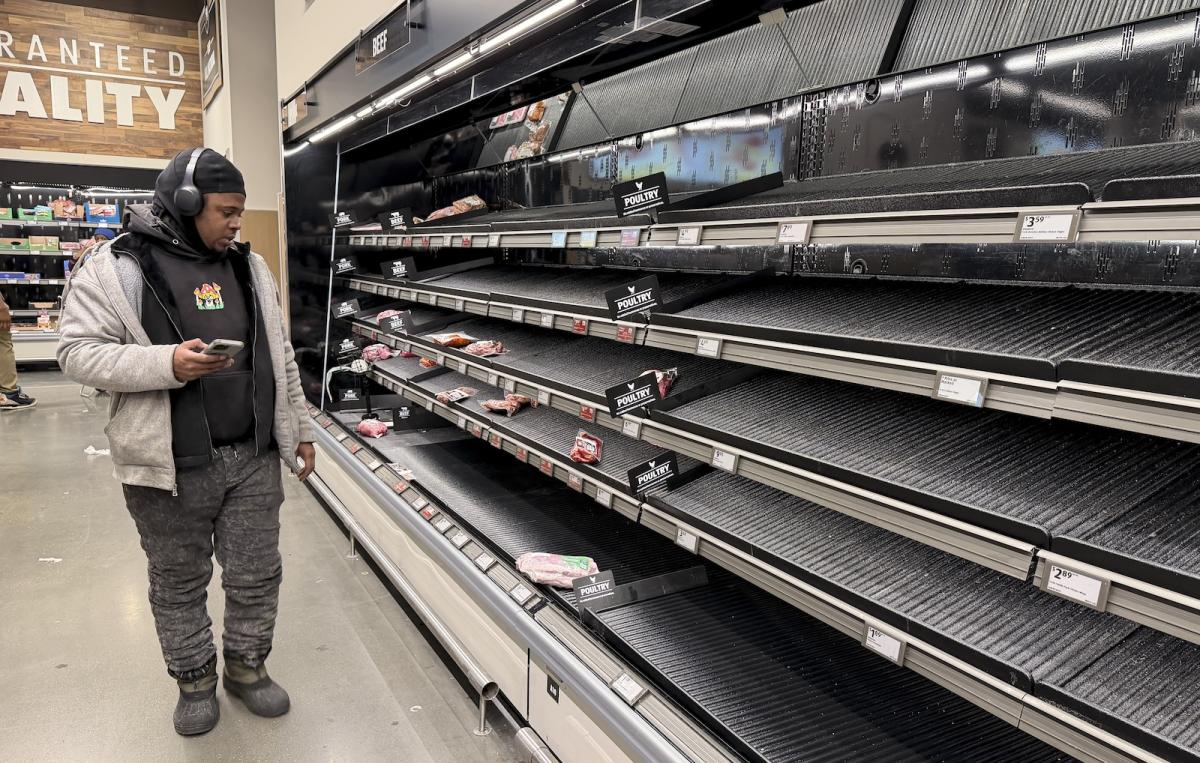 People shop at a supermarket as shelves are left empty